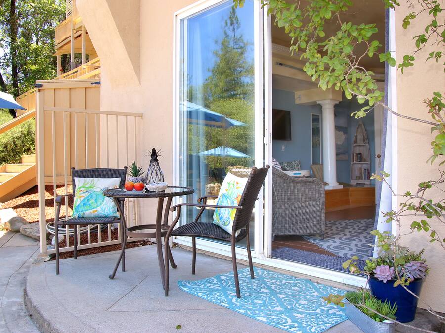 Eine Terrasses mit Korbstühlen, einem kleinen Tisch und einem blauen Teppich mit Muster.