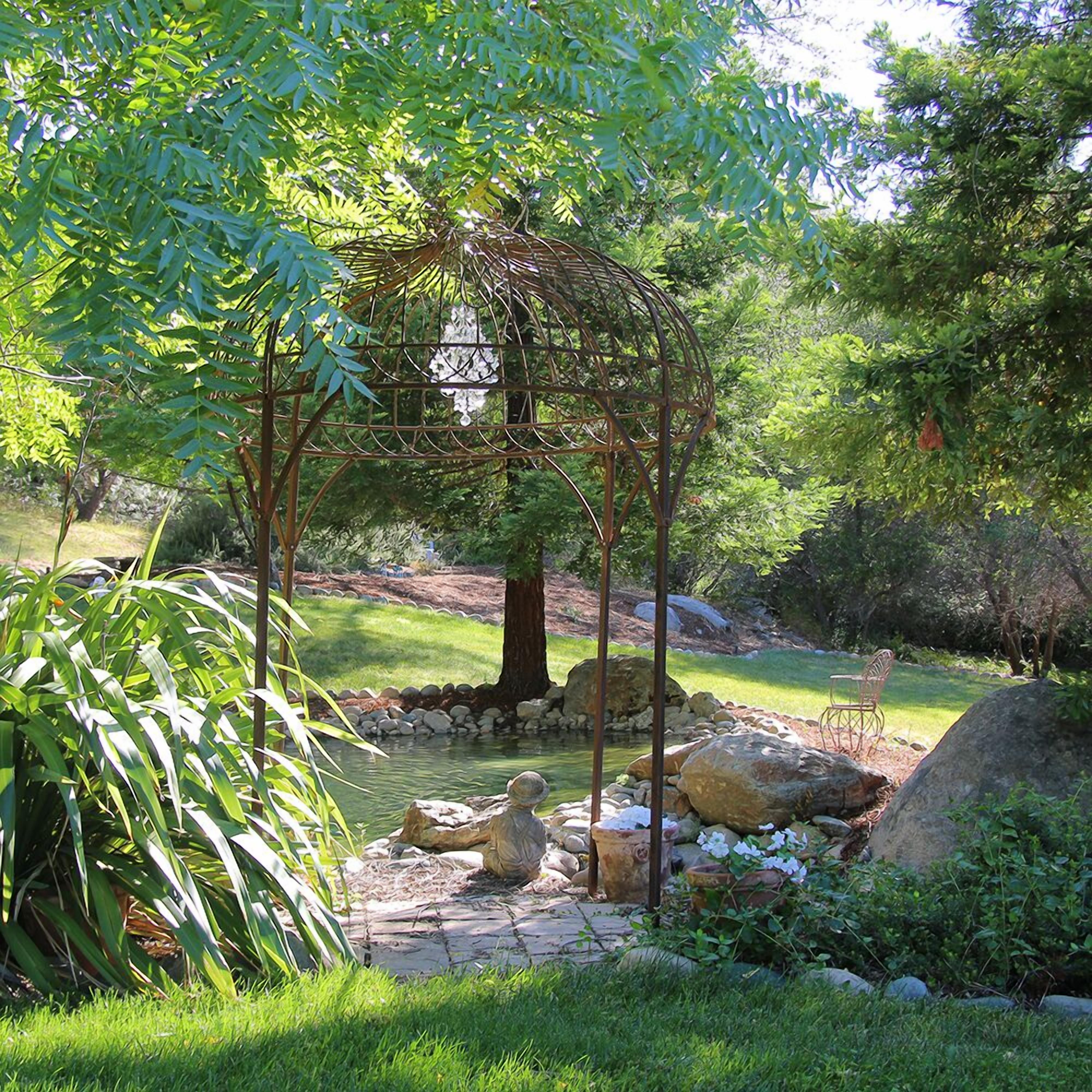 A garden with a pergola structure, a pond, and a seating area with a chair.