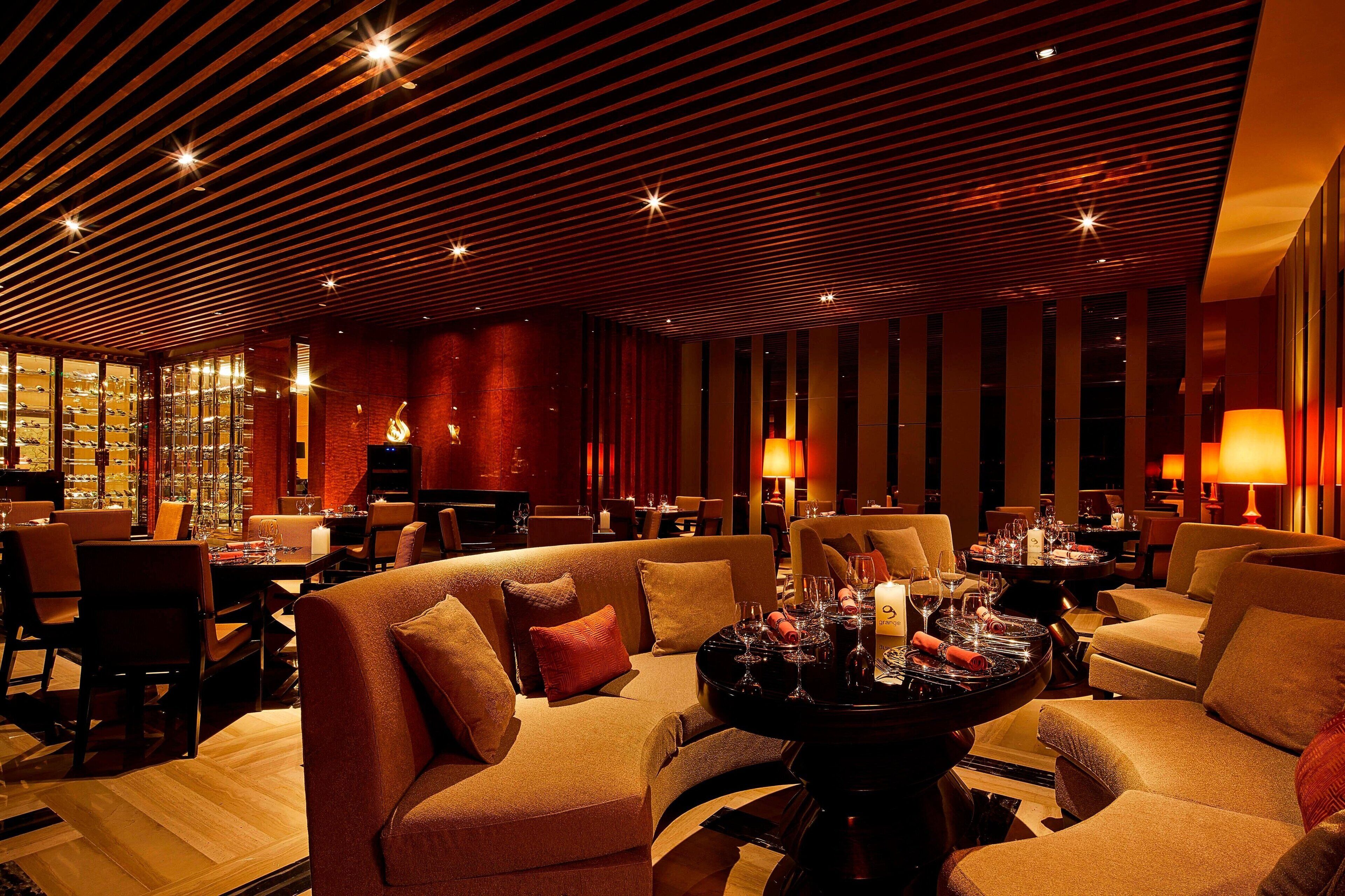 A modern restaurant with a curved seating arrangement, ambient lighting, and a warm color palette.