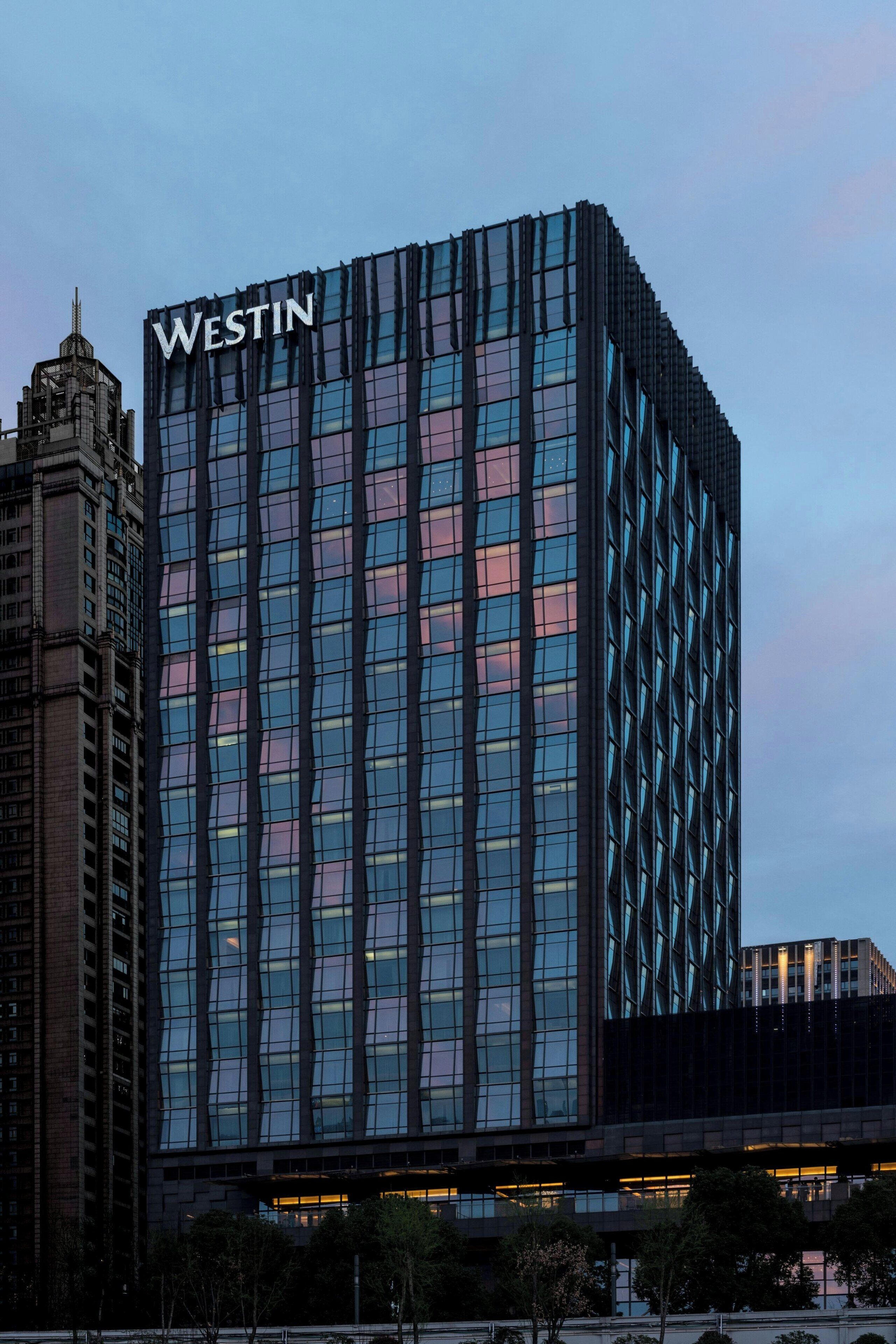 A modern Westin hotel building with a prominent 'WESTIN' sign at the top, featuring a grid-like facade with reflective glass windows.