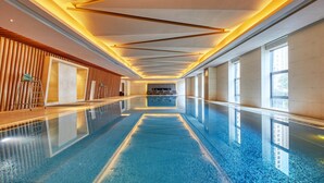 Une longue et étroite piscine intérieure, dotée d’un sol réfléchissant, de lambris en bois d’un côté et de grandes fenêtres de l’autre.