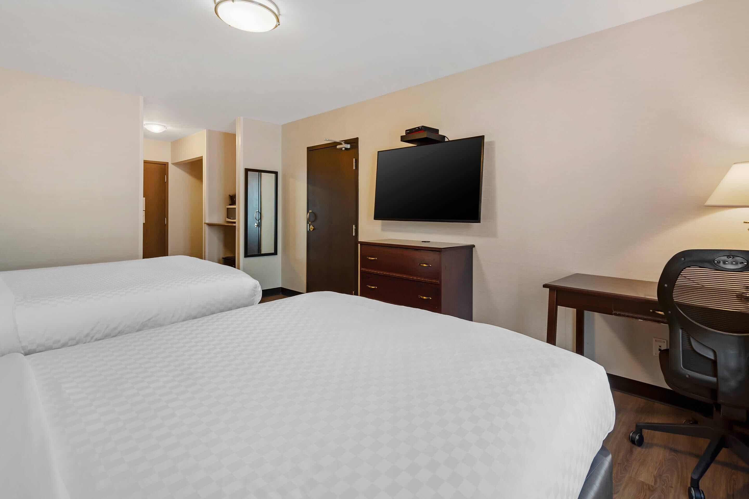 Une chambre d’hôtel avec deux lits, une télévision, un bureau et une chaise.