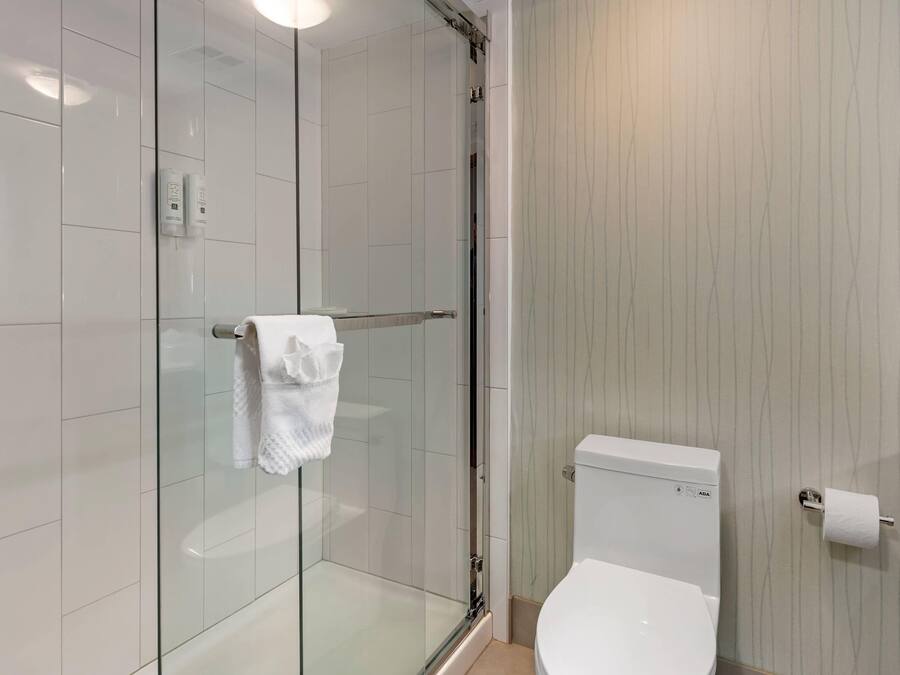 Un baño moderno con cabina de ducha de vidrio, inodoro y perchero.