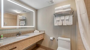 A bathroom with a granite countertop, a sink, a toilet, a towel rack, and a mirror.
