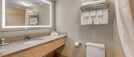 A bathroom with a granite countertop, a sink, a toilet, a towel rack, and a mirror.