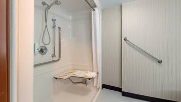 A shower with a handheld showerhead, a handheld shower, and a grab bar.
