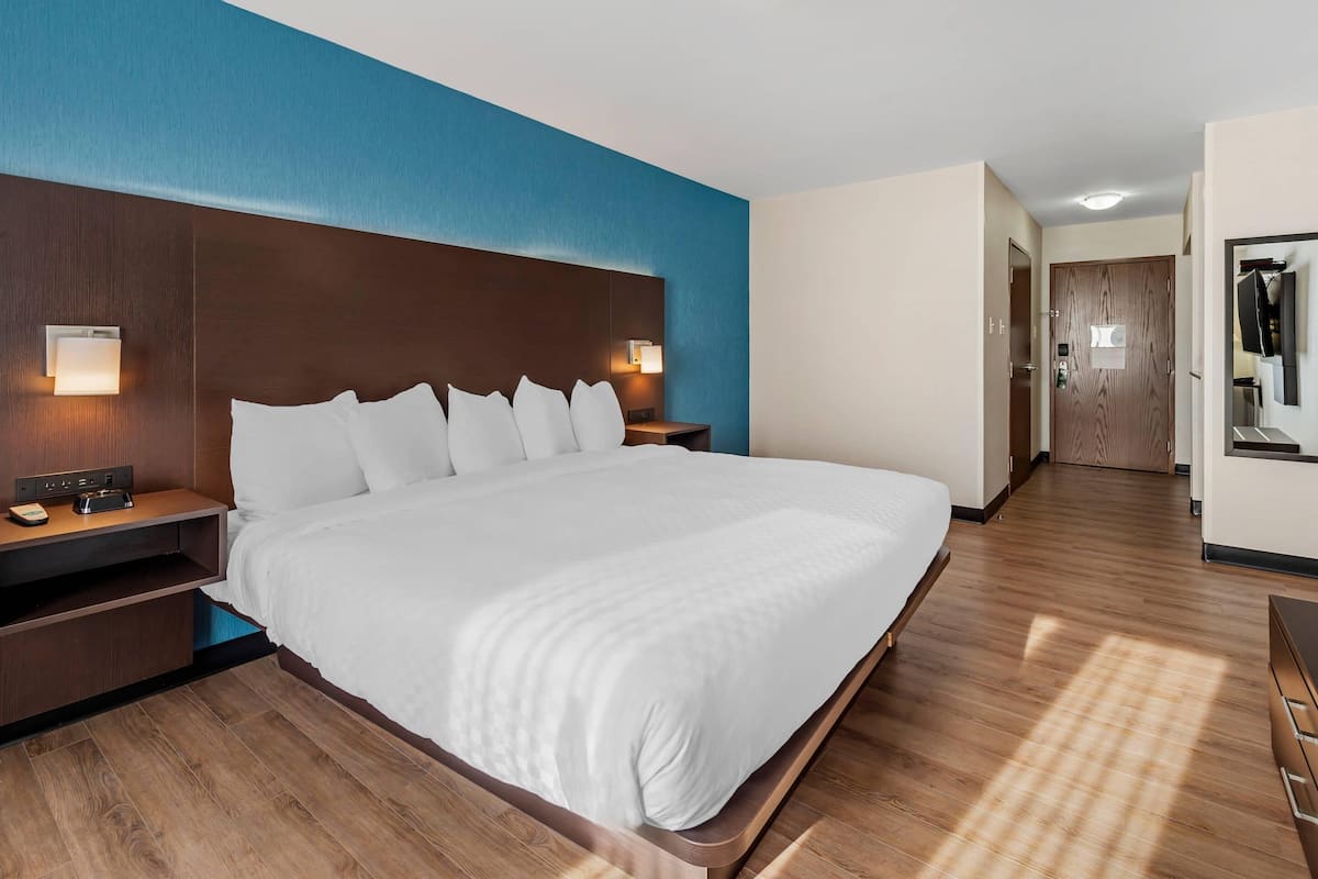 Habitación de hotel con una cama grande, cabecero de madera, lámparas de noche y un armario.