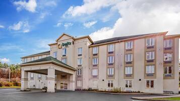 Un hôtel à plusieurs étages doté d’une entrée couverte, de nombreuses fenêtres et d’une enseigne indiquant « Quality Inn ».