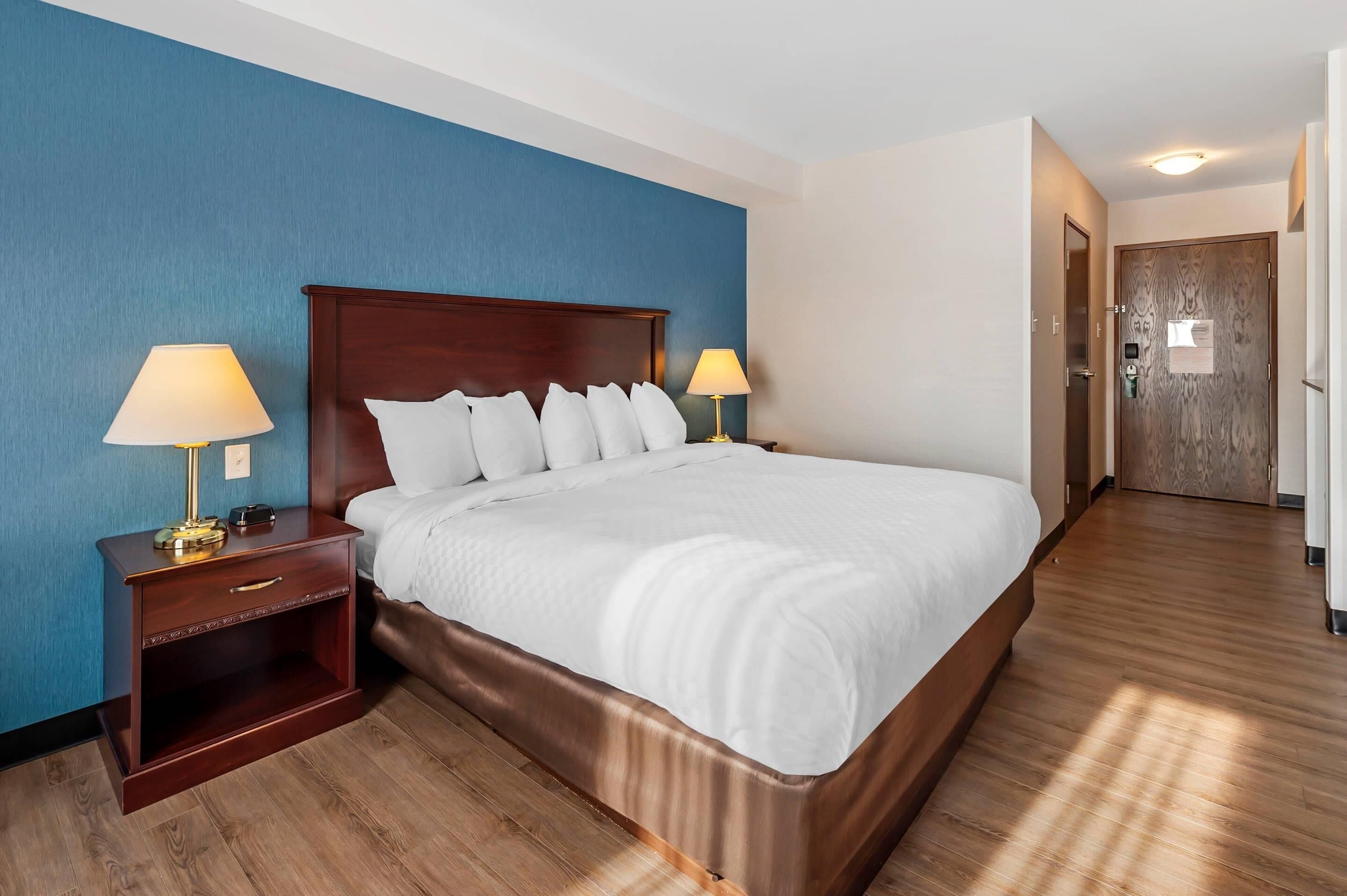 A hotel room with a large bed, wooden nightstands, and a blue accent wall.
