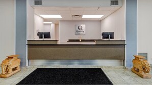 Ein Empfangsschalter mit einem 'Quality by Choice Hotels'-Schild, zwei Computermonitore und einem schwarzen Teppich.