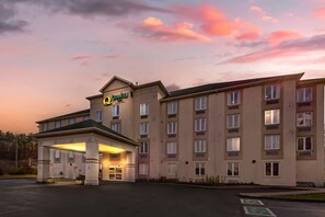 Un hotel de varios pisos con entrada cubierta y un letrero que indica 'Quality Inn'.