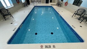 Ein Schwimmbecken mit flachem Bereich, umgeben von Stühlen und einer Uhr an der Wand.