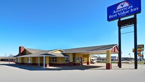 Edifici de dues plantes amb façana groga i vermella, zona de pàrquing coberta i un rètol de America's Best Value Inn.