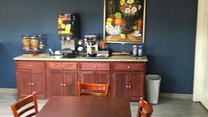 Una zona de menjador amb una taula i caires de fusta, una màquina de cafè i un quadre a la paret.