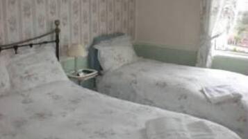 Habitació amb dos llits individuals, una tauleta de nit i una finestra amb cortines.
