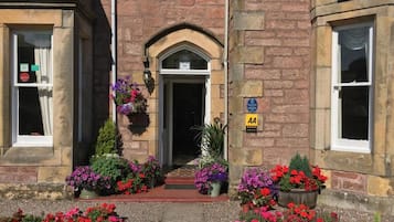 A stone building with a central entrance, numbered 10, and a sign indicating AA accommodation.