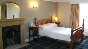 Une chambre à coucher bien aménagée, avec un lit en bois, une cheminée, une table de chevet et une lampe fixée au mur.