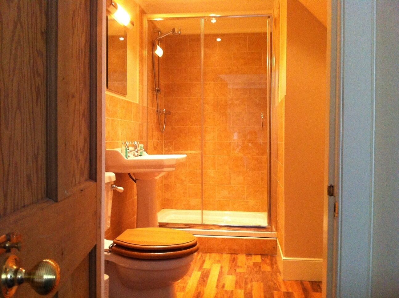Un bagno con doccia vetro, lavandino e water.