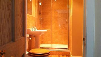 Un bagno con doccia vetro, lavandino e water.