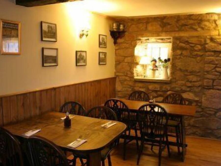 Un espace repas agrémenté d’un mur en pierre, de lambris en bois et de tableaux encadrés.