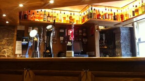 Un espace bar avec un assortiment de bouteilles d’alcool, une tireuse à bière Guinness et une enseigne de couleur dorée.