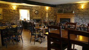 Un restaurant aux murs de pierre, aux tables et aux chaises en bois.