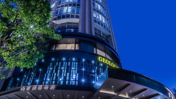 Un hotel moderno con fachada curva, amplios ventanales y una entrada destacada con una fuente.
