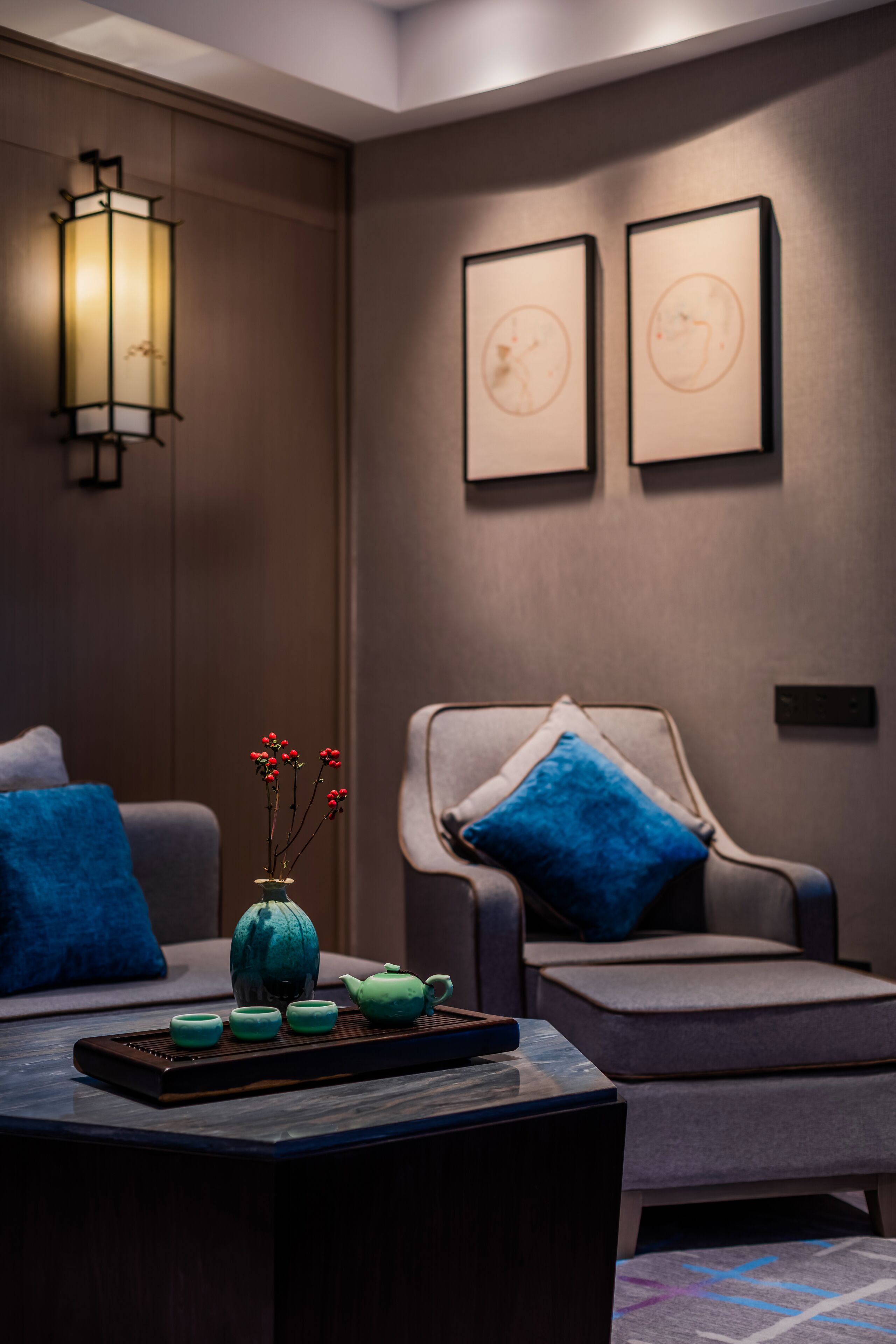 A modern room with a sofa, armchair, and a table with a teapot and cups.