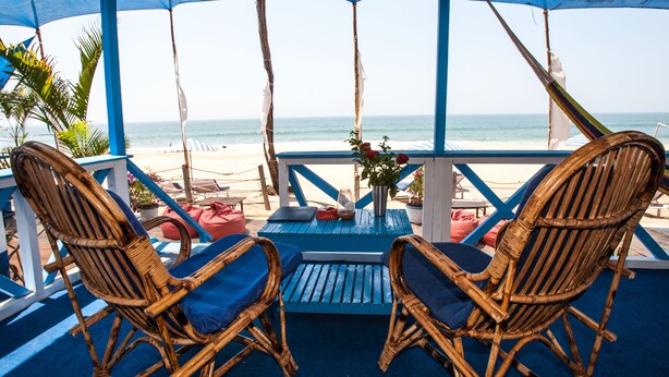 A beachside seating area with wicker chairs and a table, overlooking the ocean. - Cuba Agonda (Canacona)