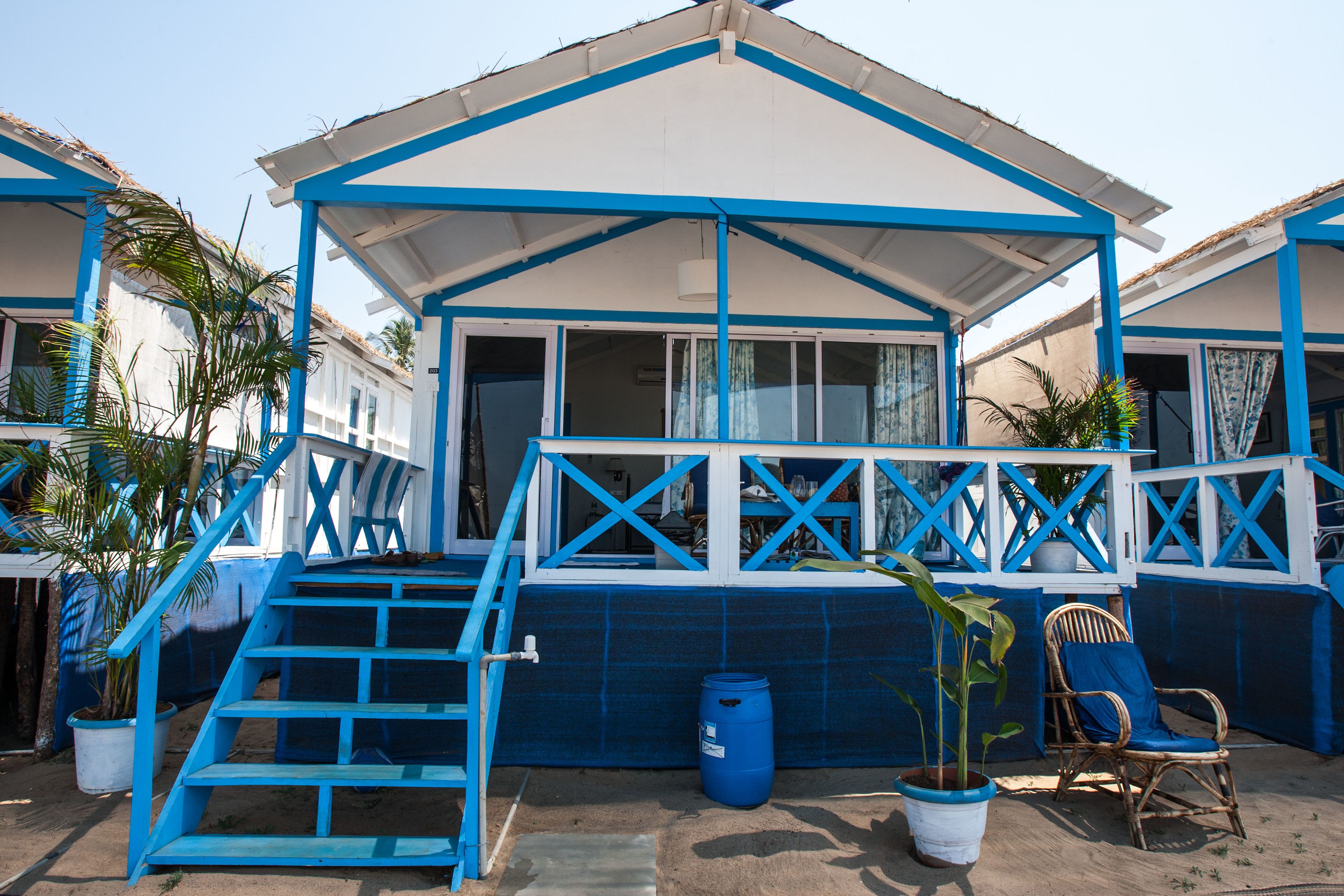 A beachfront property with a covered patio, potted plants, and a chair.