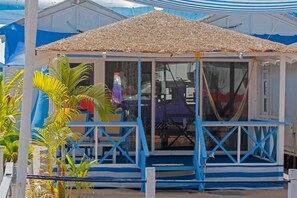 A beach hut with a thatched roof, glass doors, and blue railings. - Cuba Agonda (Canacona)