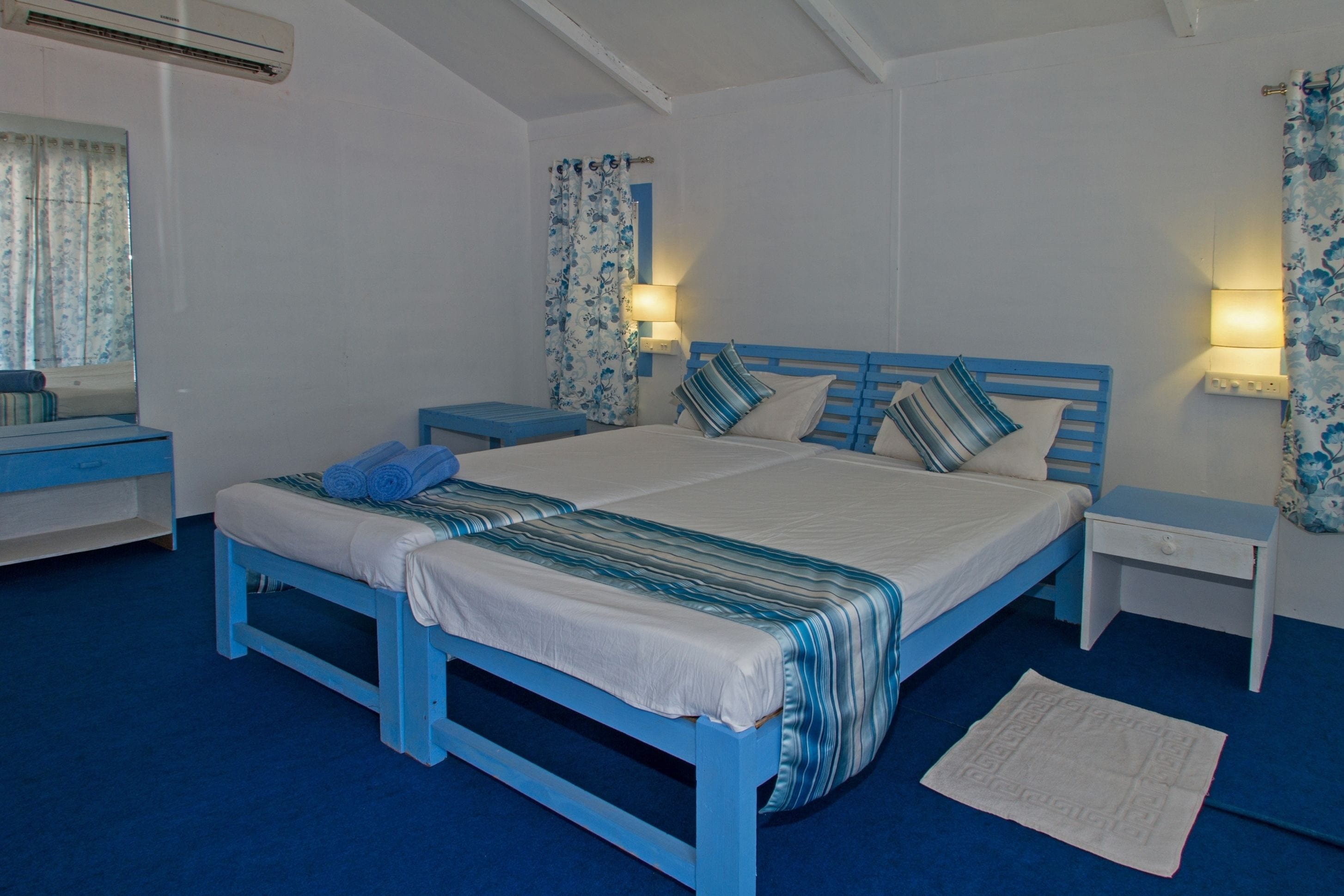 A bedroom with a blue bed, white walls, and matching blue nightstands.