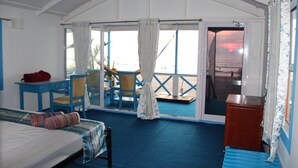 A room with a bed, a desk, and chairs. There is a view of the outside through a glass door. - Cuba Agonda (Canacona)