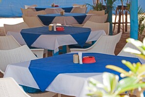 Outdoor tables with blue and white tablecloths, wicker chairs, and a blue column. - Cuba Agonda (Canacona)