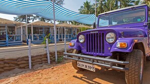 A purple Mahindra vehicle parked in front of a building with a striped awning. - Cuba Agonda (Canacona)