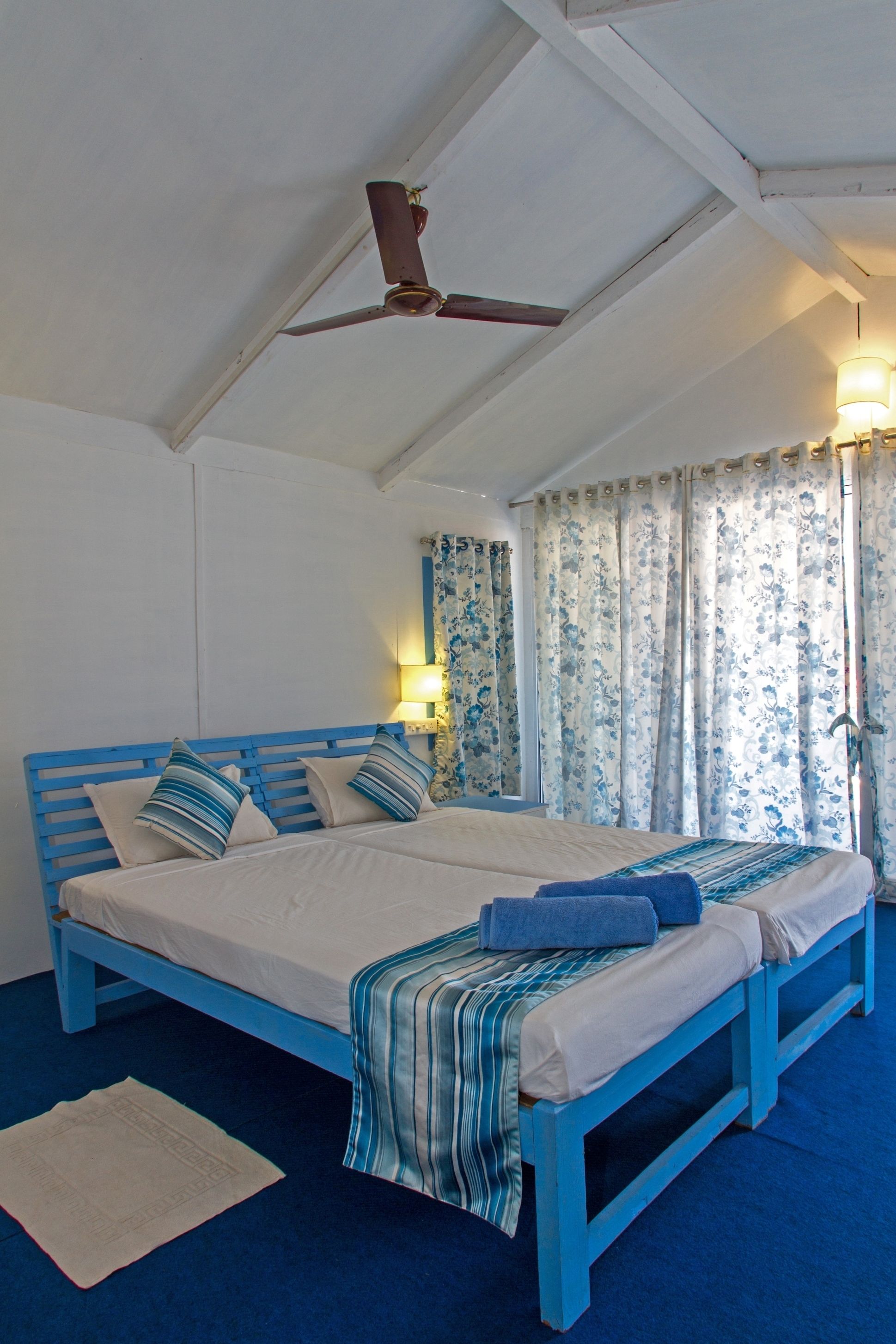 A bedroom with a large bed, a ceiling fan, and floral curtains.