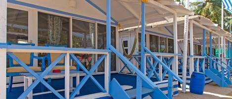 A beachside building with blue and white exterior, featuring outdoor seating and a staircase leading to an upper deck.