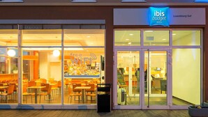 Un hôtel à l’architecture moderne, doté de grandes fenêtres et d’une enseigne indiquant qu’il fait partie de la chaîne ibis budget.