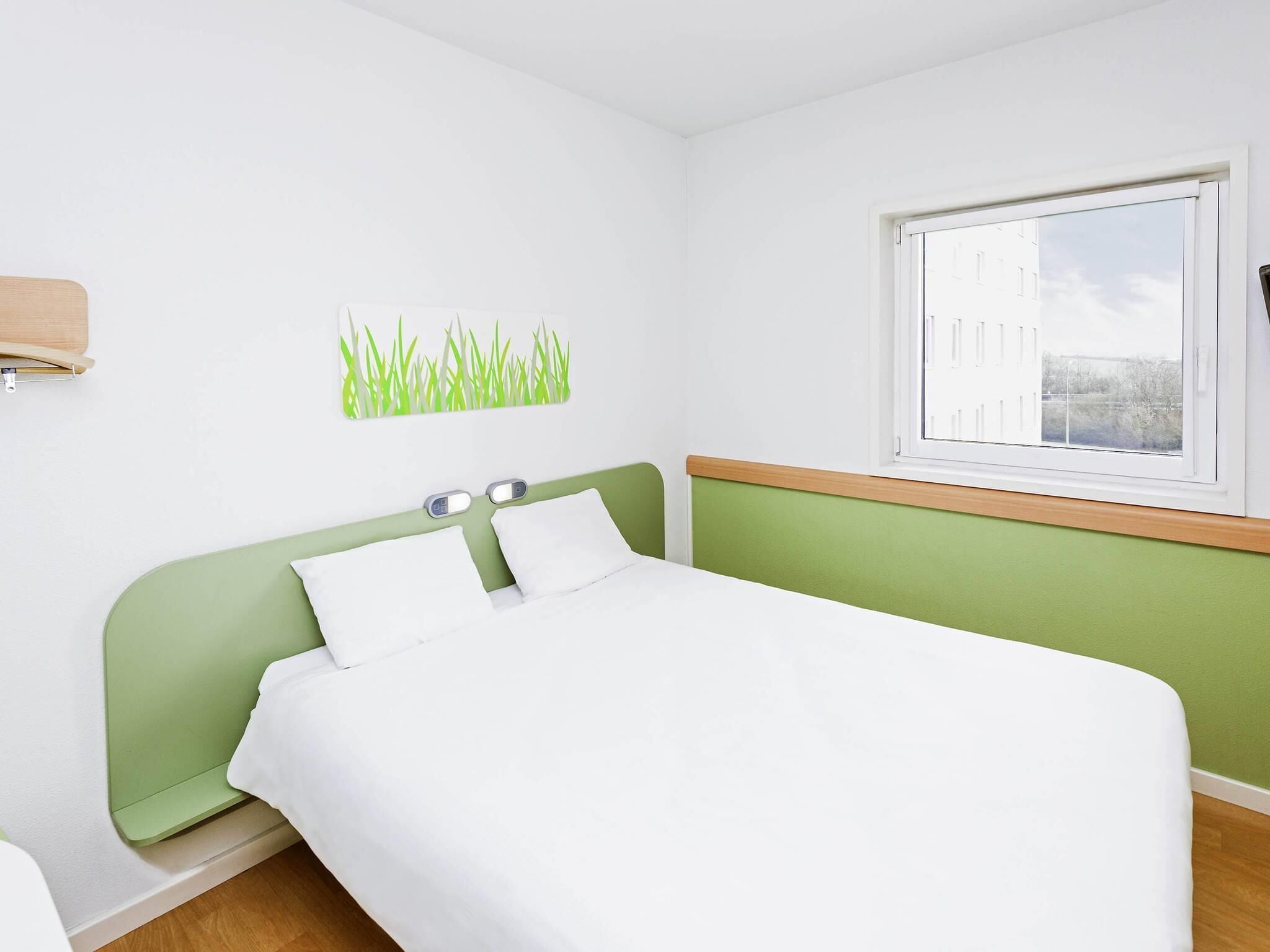 A bedroom with a bed, a window, and a wall-mounted scale.