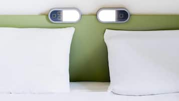 Uma cama com almofadas brancas e uma parede verde.