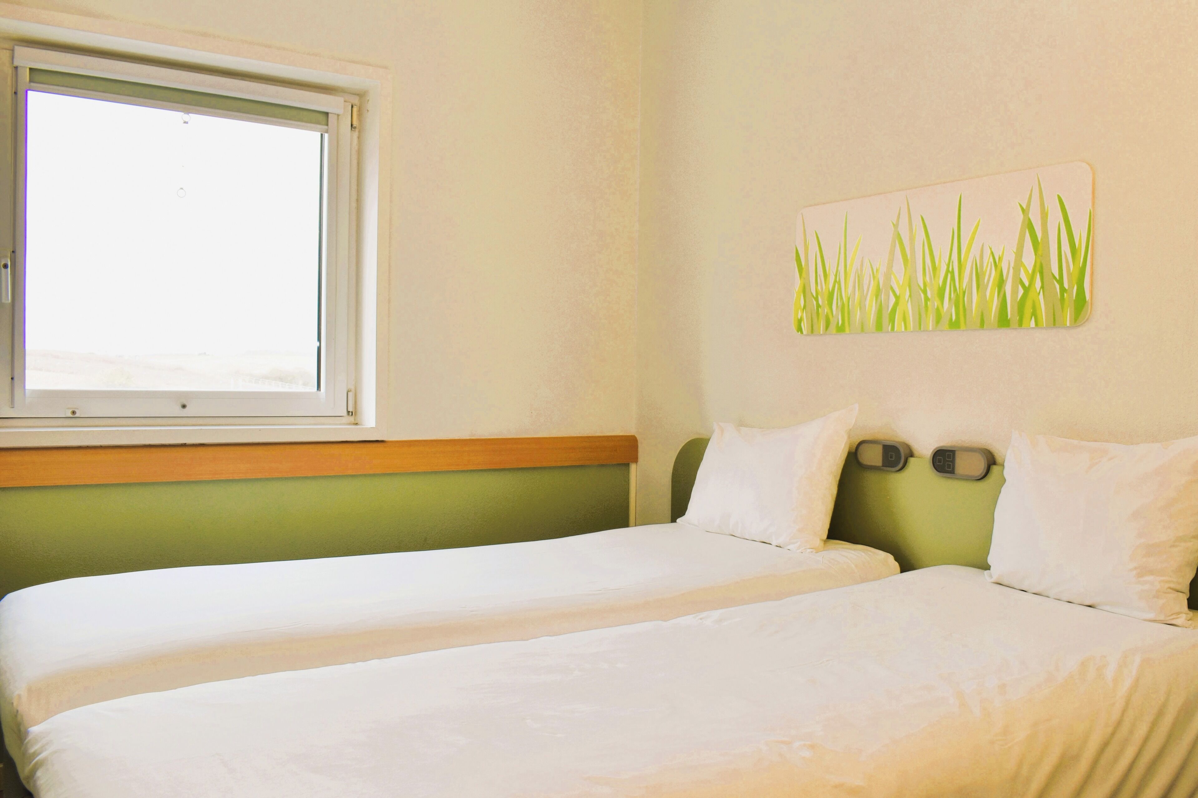 Una habitación con dos camas, una ventana y un reloj de pared.