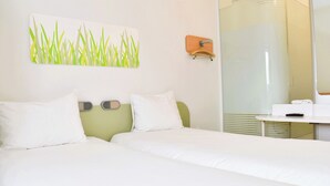 Une chambre d’hôtel avec deux lits, une salle de bain avec une douche en verre et une œuvre d’art accrochée au mur.