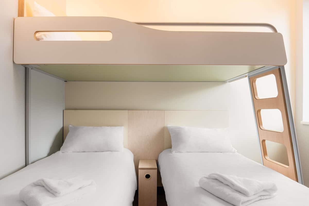 A bunk bed room with two beds, each with a pillow and a folded towel.