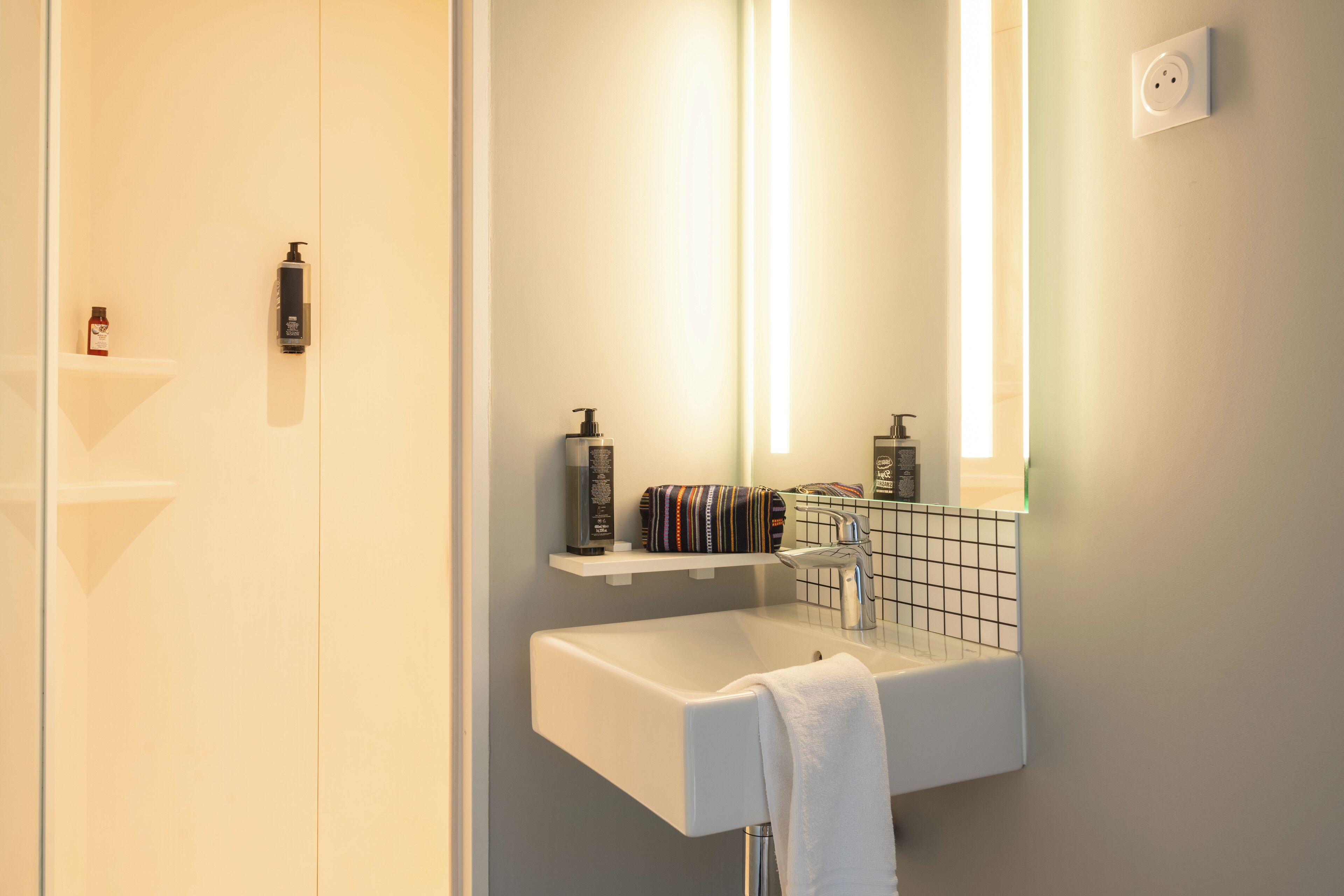 Une salle de bain moderne avec un lavabo blanc, un miroir et une serviette accrochée au mur.