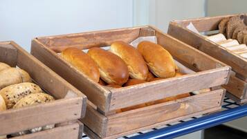 Cajas de madera con panes y pasteles varios sobre una estantería metálica.