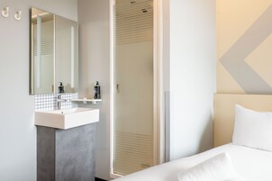 Un baño moderno con un espejo grande, un lavamanos y una ducha.