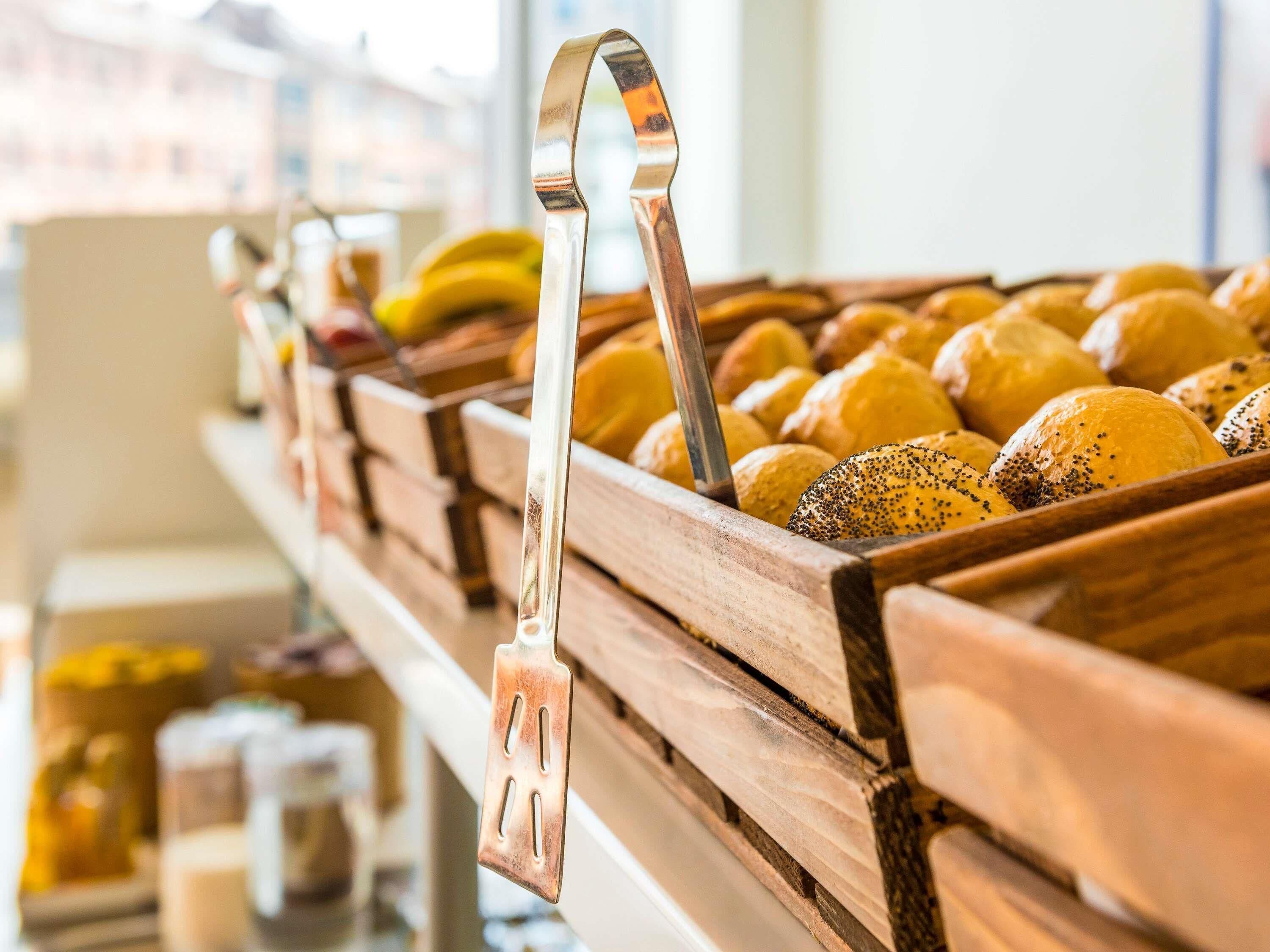 Een bakkerijdisplay met brood en gebak, een metalen hendel en een houten toonbank.