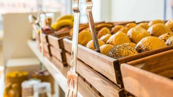 Een bakkerijdisplay met brood en gebak, een metalen hendel en een houten toonbank.