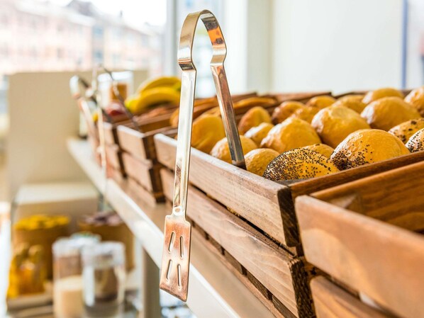 Una vitrina de panadería con panes y pasteles, un asa metálica y un mostrador de madera.