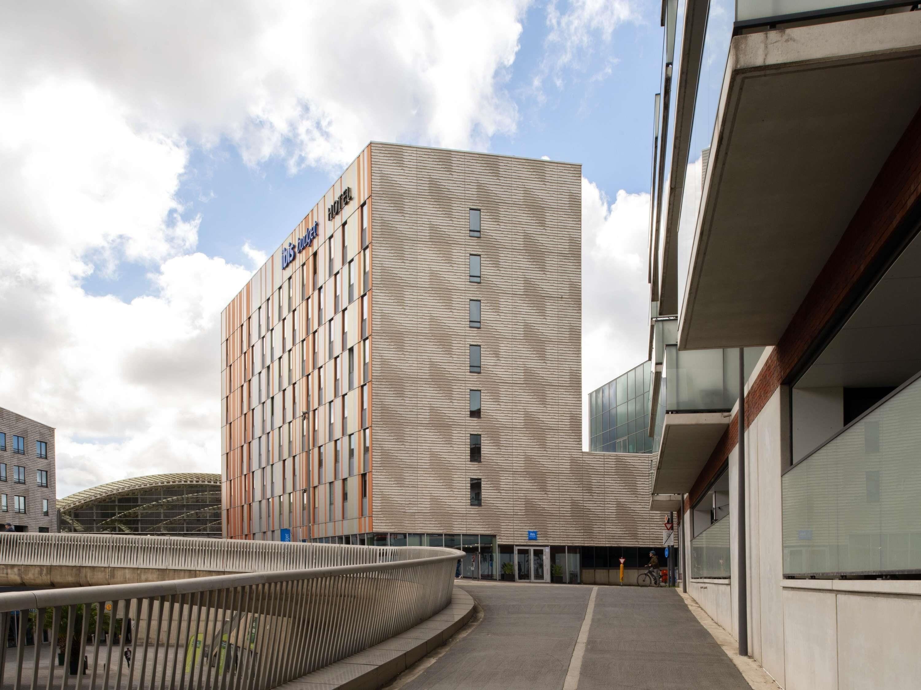 A modern hotel building with a textured facade and a clear sky.